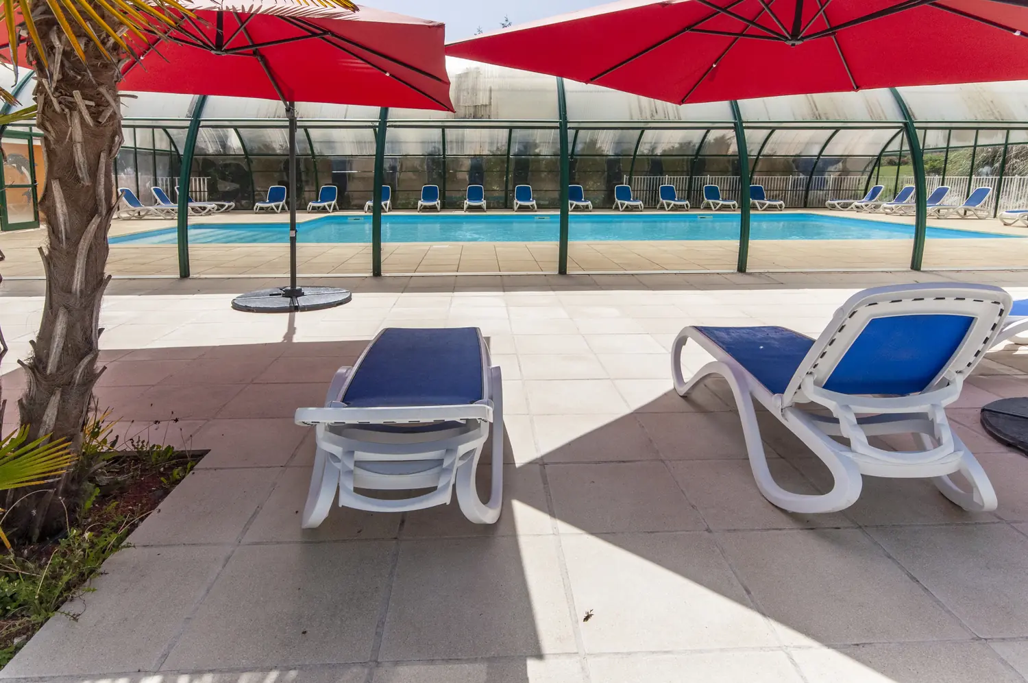 Terrasse extérieure de la piscine avec parasols rouges et transats